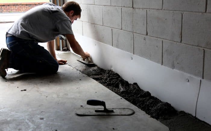 Castle Dream technician finishing concrete over a newly installed interior perimeter drain